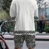 Men's casual vacation style set, white diamond patterned V-neck mid sleeved top paired with black and white geometric printed shorts